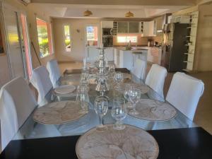 a dining room table with wine glasses and white chairs at Casa AONIKENK in Villa Dolores