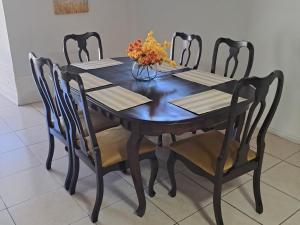 a dining room table with four chairs and a vase of flowers at Roxel Home in Baños