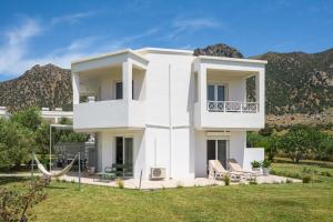 a white house with mountains in the background at Einalia Holiday Homes by the Beach in Kardamaina