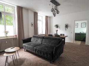 a living room with a black couch and a table at Idylle Apartments - Suite Kaisergrün in Bad Ems