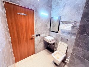 a bathroom with a toilet and a wooden door at Hotel Purple Lotus Suites in Chauk