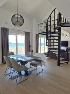 a dining room with a table and chairs and a spiral staircase at Apartmani Zora in Primošten
