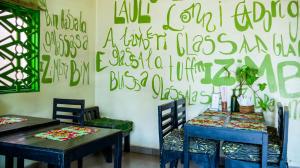 two tables and chairs in a room with graffiti on the wall at SuPas Bistro in Kisoro +24 photos