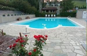 a swimming pool with red roses in front of it at Appartamento al Feudo-piscina e parcheggio gratuito in Asti