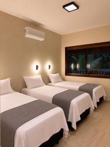 a hotel room with three beds and a window at Pousada Jamacaii in Araxá +22 photos