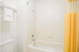 a white bathroom with a shower and a white toilet at A Red Dot Inn Milledgeville in Milledgeville