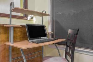 a laptop computer sitting on a desk with a chair at A Red Dot Inn Milledgeville in Milledgeville
