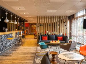 a lobby with a couch and tables and chairs at ibis Saint-Malo Madeleine in Saint Malo