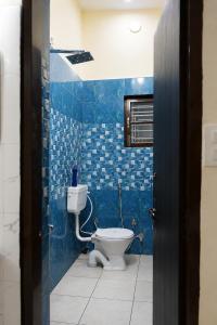 a bathroom with a toilet and a blue tiled wall at Homies Homestay Boys Hostel in Kurukshetra