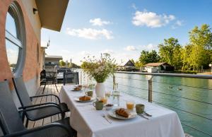 a table with plates of food and a view of a river at Sunset view Housboat with sundeck,AC&Heating in Bratislava