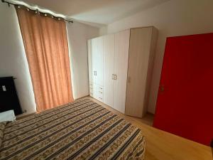 a bedroom with a bed and a red door at Casa Lina in Cavalese