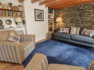a living room with two couches and a stone wall at Pegs in Porthleven