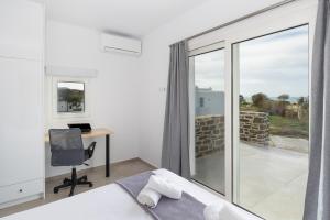 a bedroom with a bed and a desk and a window at Naxos Cube Villa Panoramic Views Maisonette with Sea View 2 min walk to Plaka Beach in Plaka