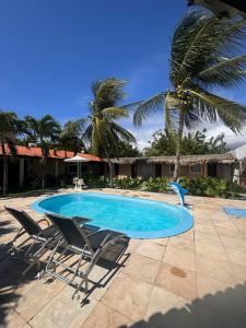 a swimming pool with two chairs and a palm tree at Pousada Marúa Fortaleza in Fortaleza