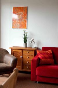 a living room with a red couch and a red chair at Nordnordwest in Langeoog