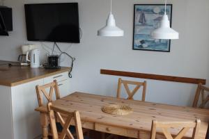 a kitchen with a wooden table with chairs and a tv at Nordnordwest in Langeoog