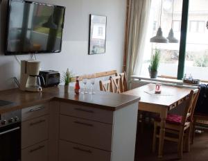 a kitchen with a table and a television on the wall at Nordnordwest in Langeoog +20 photos