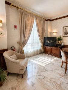 ein Wohnzimmer mit Sofa, Fernseher und Fenster in der Unterkunft Hotel Posta in Cecina
