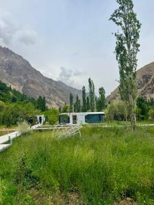 a house in a field of grass with mountains in the background at ZEVS-Holiday Complex in Deu