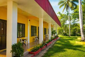 an exterior view of a yellow house with palm trees at Jurisu Resort in San Vicente