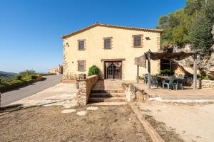 an old stone house with a table in front of it at Masia Puigadoll in Rodonyà