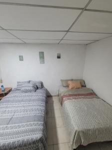 two beds sitting next to each other in a room at Hospedaje céntrico in Zacatecoluca