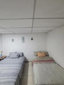 two beds sitting next to each other in a room at Hospedaje céntrico in Zacatecoluca