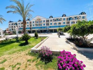 a large white building with palm trees and pink flowers at Hurghada HuB in Hurghada
