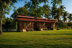 a house with a red roof on a grass field at Jurisu Resort in San Vicente