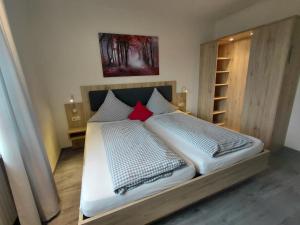 a bedroom with a bed with white sheets and red pillows at Pension Karin in Breitengüßbach