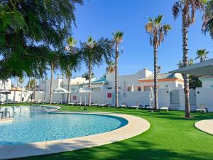 a resort with a swimming pool and palm trees at ON City Apartments in Matalascañas