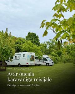 two white vans parked in a park with trees at Pühajõe Puhkemaja in Pühajõe