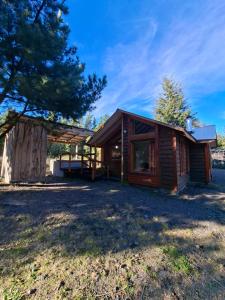 a log cabin with a porch and a tree at Refugio entre Coihues in Melipeuco