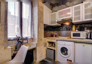 a kitchen with a washing machine and a microwave at Sous mon toit - Sauna & jacuzzi in Dijon