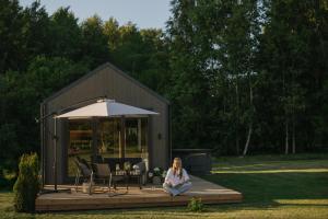 a woman sitting on a deck in front of a shed at Ruoliškis tiny house in Biržai