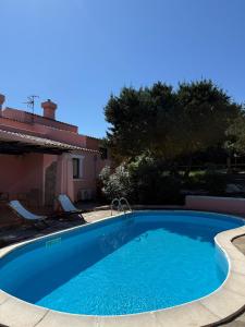 a large blue swimming pool next to a house at Villa LUMIè Stintino in Stintino