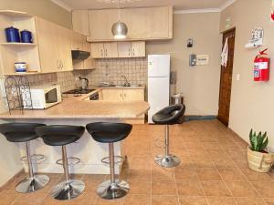 a kitchen with a counter and two bar stools at Praia Longa 4 in Rand Rifles +7 photos