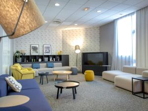 a living room with couches and a tv at Mercure Hyères Centre Côte d'Azur in Hyères