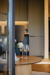 two glasses of wine sitting on a wooden table at Ruoliškis tiny house in Biržai