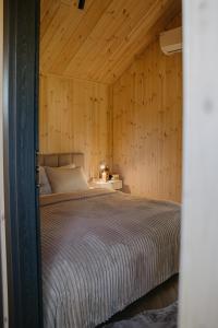 a bedroom with a bed in a wooden wall at Ruoliškis tiny house in Biržai