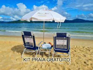 two chairs under an umbrella on the beach at Belle Arti Pousada in Florianópolis