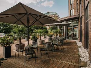 an outdoor patio with tables and chairs and umbrellas at Mercure Hotel Hamburg City in Hamburg