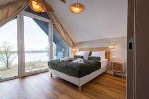 a bedroom with a large bed and large windows at Sen Topoli - Domy nad jeziorem I Sauna I Plaża I 30 min od Torunia in Mirakowo