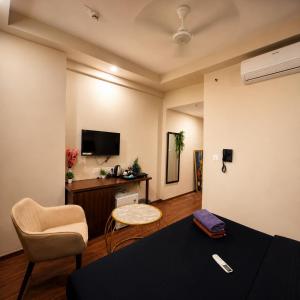 a living room with a table and chairs and a tv at Glow Corner in Greater Noida