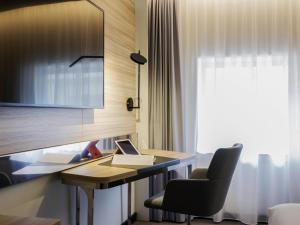 a room with a desk with a laptop and chairs at Novotel Den Haag City Centre in The Hague +130 photos