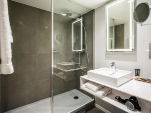 a bathroom with a sink and a shower at Novotel Den Haag City Centre in The Hague