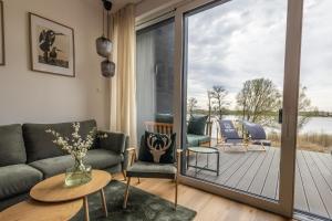 a living room with a couch and a glass door at Sen Topoli - Domy nad jeziorem I Sauna I Plaża I 30 min od Torunia in Mirakowo