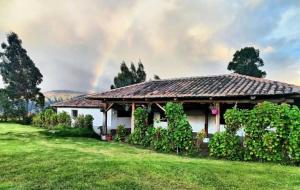 a house with a gazebo with a rainbow in the sky at Lodge La Ilusión in Ibarra