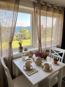 a white table with cups and bowls of fruit in front of a window at My Sweet Home in Fauske