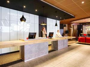 a lobby with a counter with two people sitting at it at ibis Hotel Hamburg Alster Centrum in Hamburg